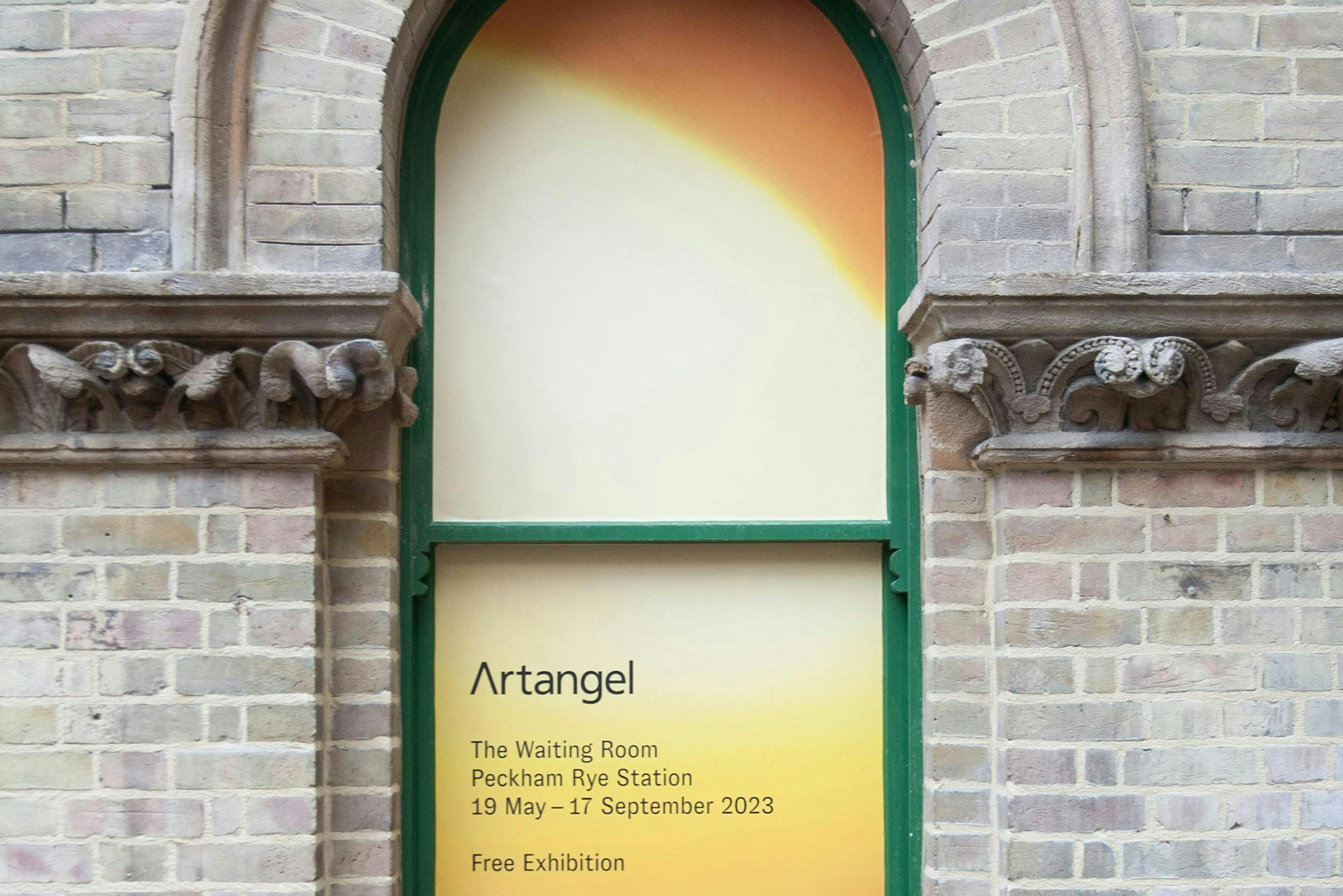 An arched window in an old brick building, the window has a yellow vinyl and text 